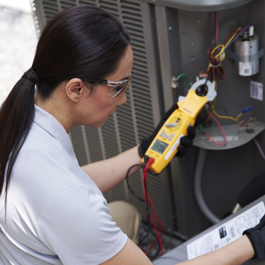 a heater repair technician using a device to check the outdoor unit