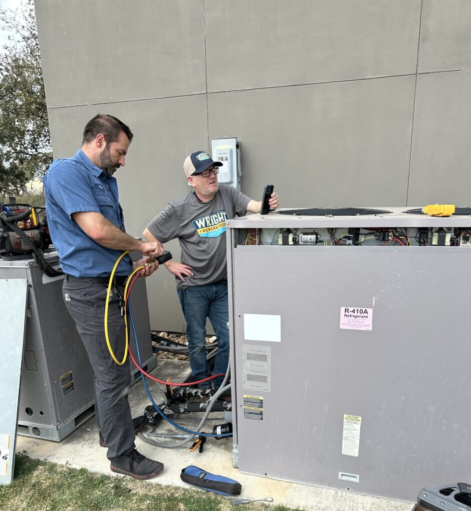 two wright ac technicians using tech tools to perform repairs on an outdoor hvac commercial unit