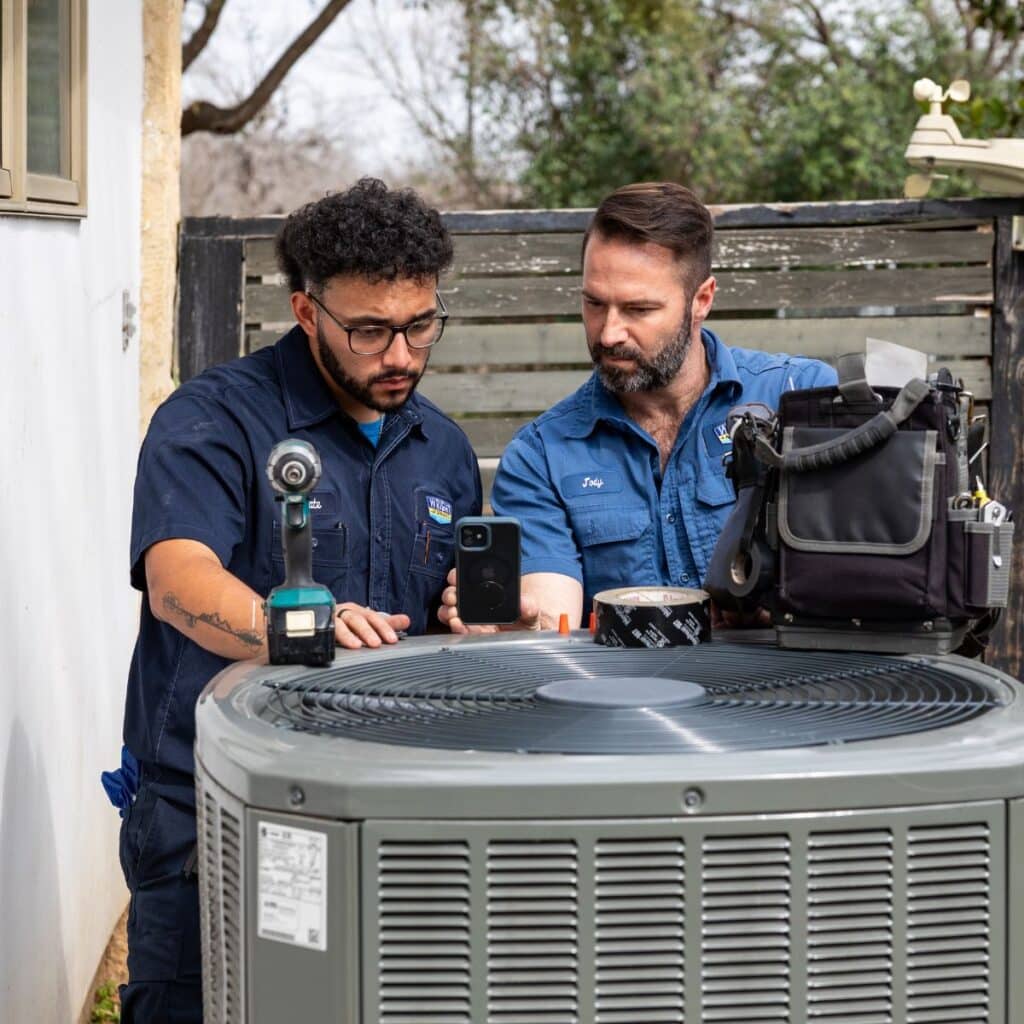 wright ac technicians collaborating on a residential outdoor hvac unit repair