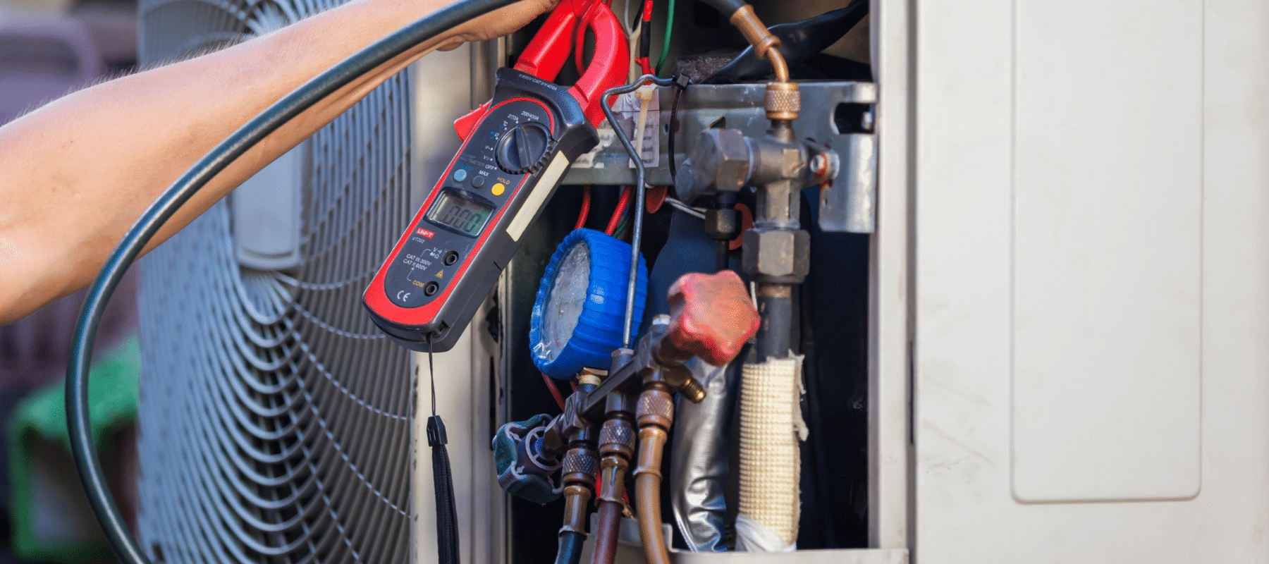 a technician using a device to check an outdoor HVAC unit during a repair