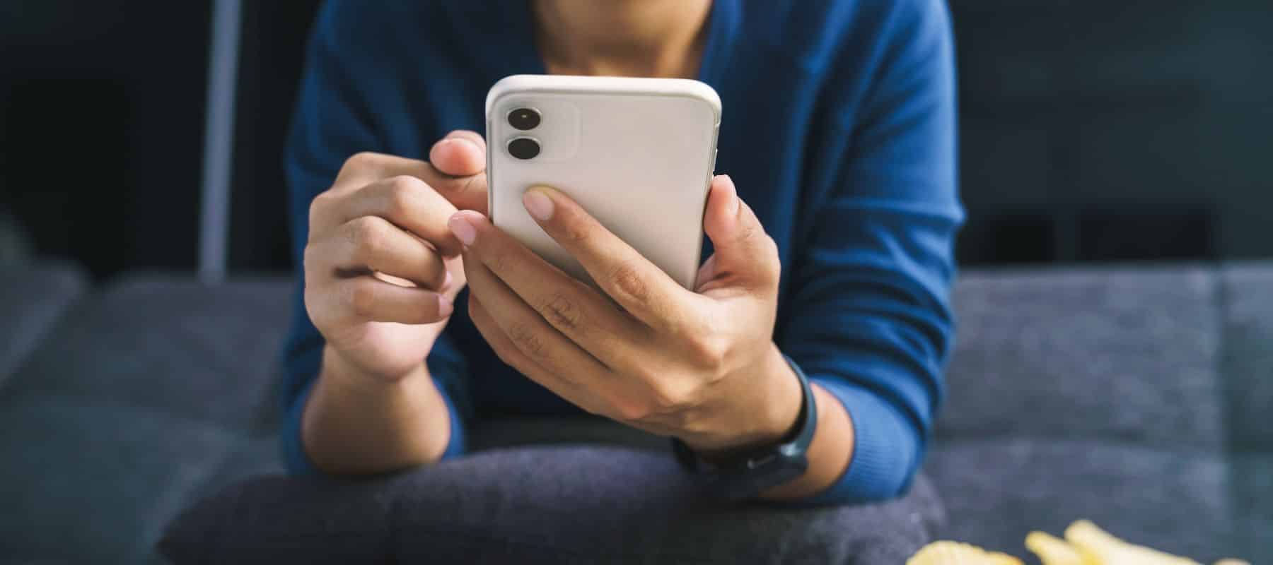 a woman in a blue shirt holding a white phone