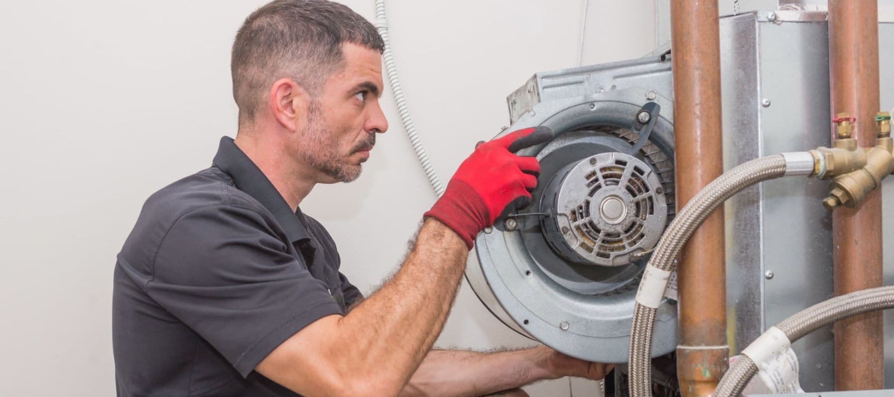 a service technician with gloved hands installing a part of a heater