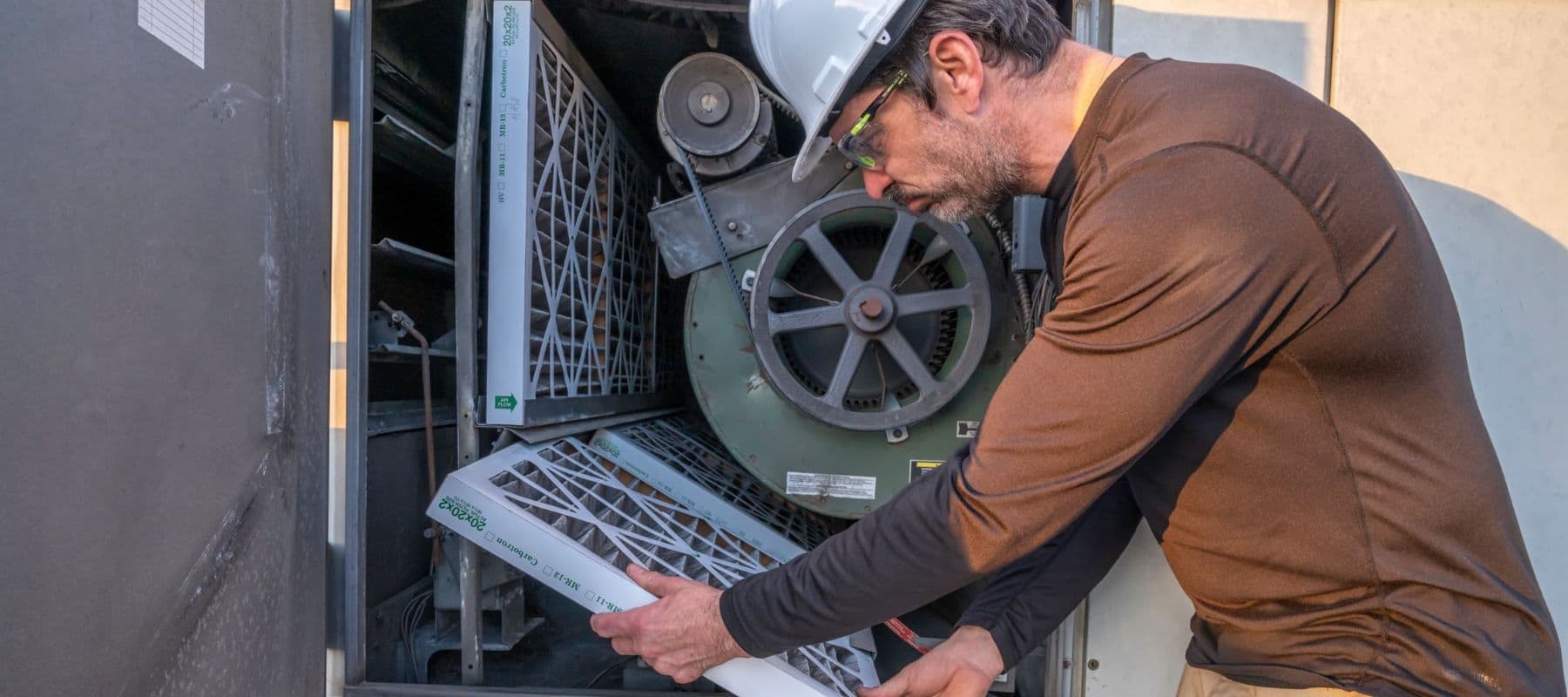 man in a brown shirt inspecting air filters during a heater replacement