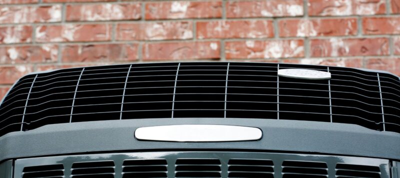 an outdoor HVAC system against a red brick wall