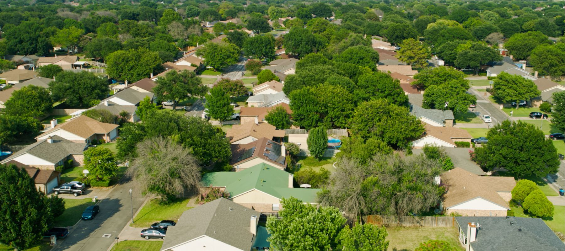 Aerial view of a suburban neighborhood with tree-lined streets and houses