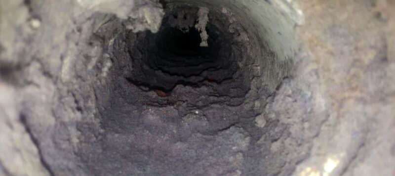 closeup of the inside of a furnace vent that is filled with dryer lint