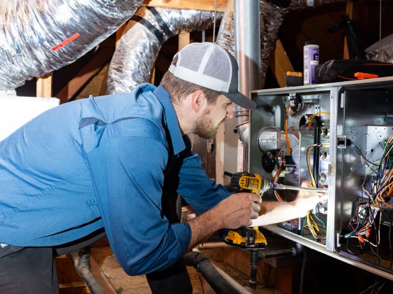 A Wright Home Services technician working on an HVAC system in an attic.