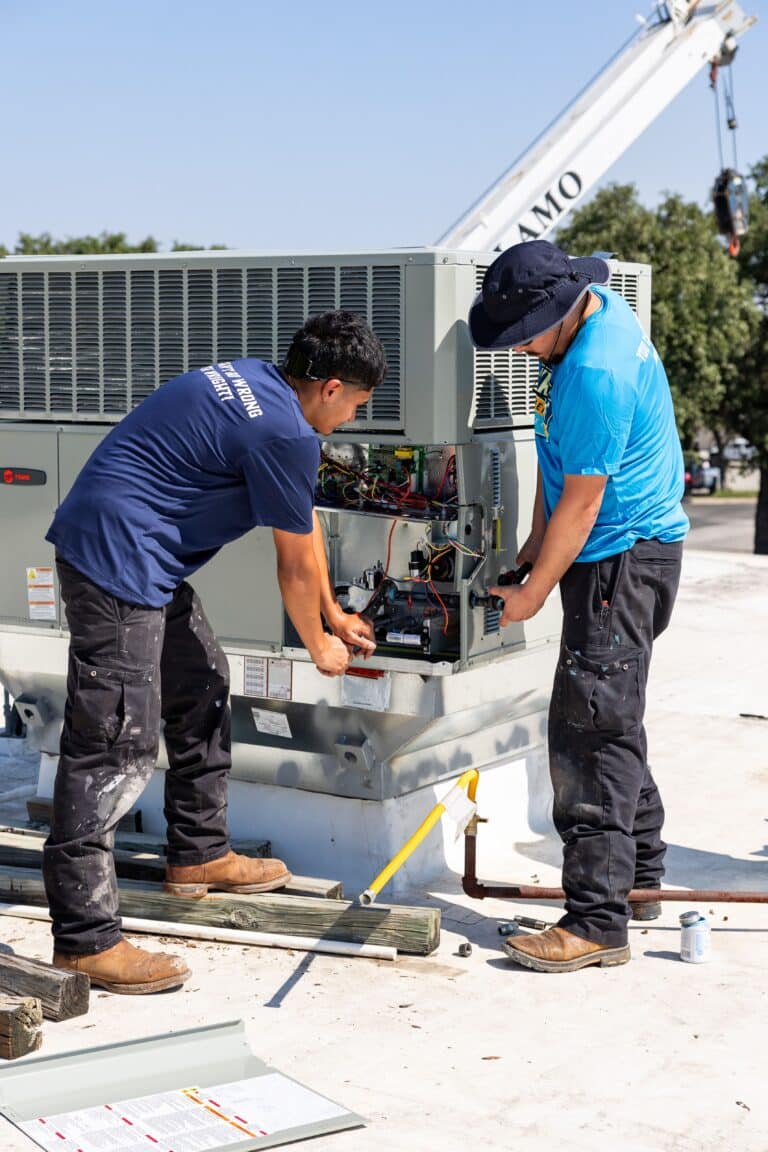 Two Wright Home Services technicians working on a newly installed HVAC system outside.