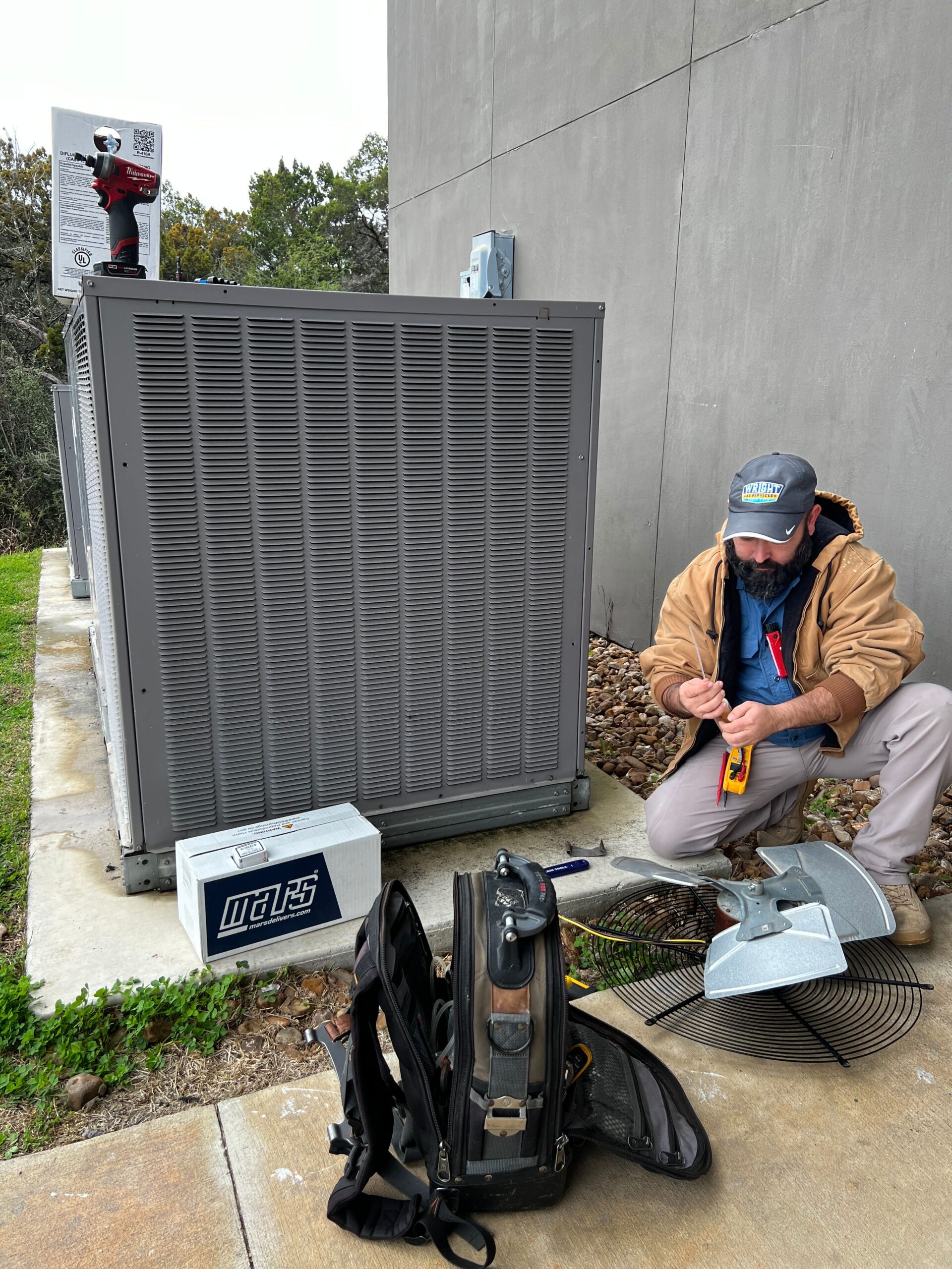 A Wright Home Services technician working on an outdoor AC unit.