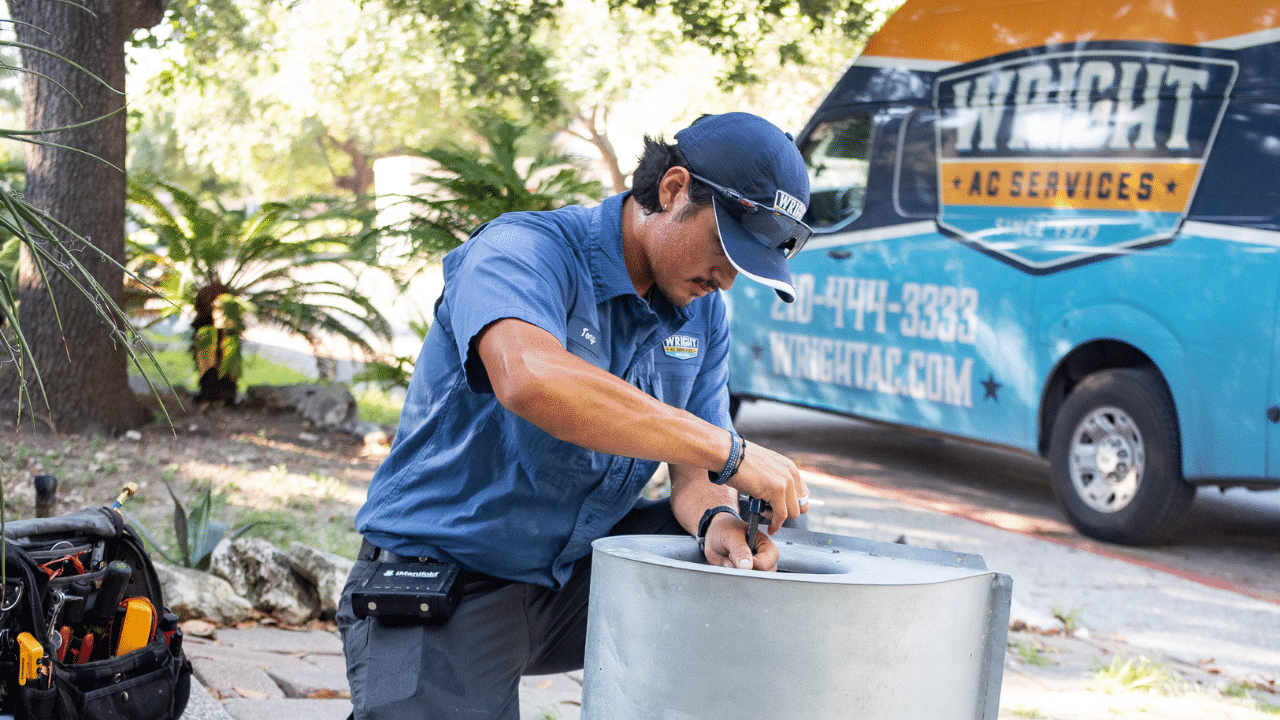 A Wright Home Services HVAC technician working on a fan blower outside of a home with the Wright truck in the background.
