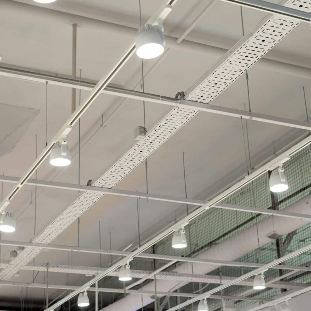 Ceiling view of commercial track lighting and exposed ductwork in an industrial space