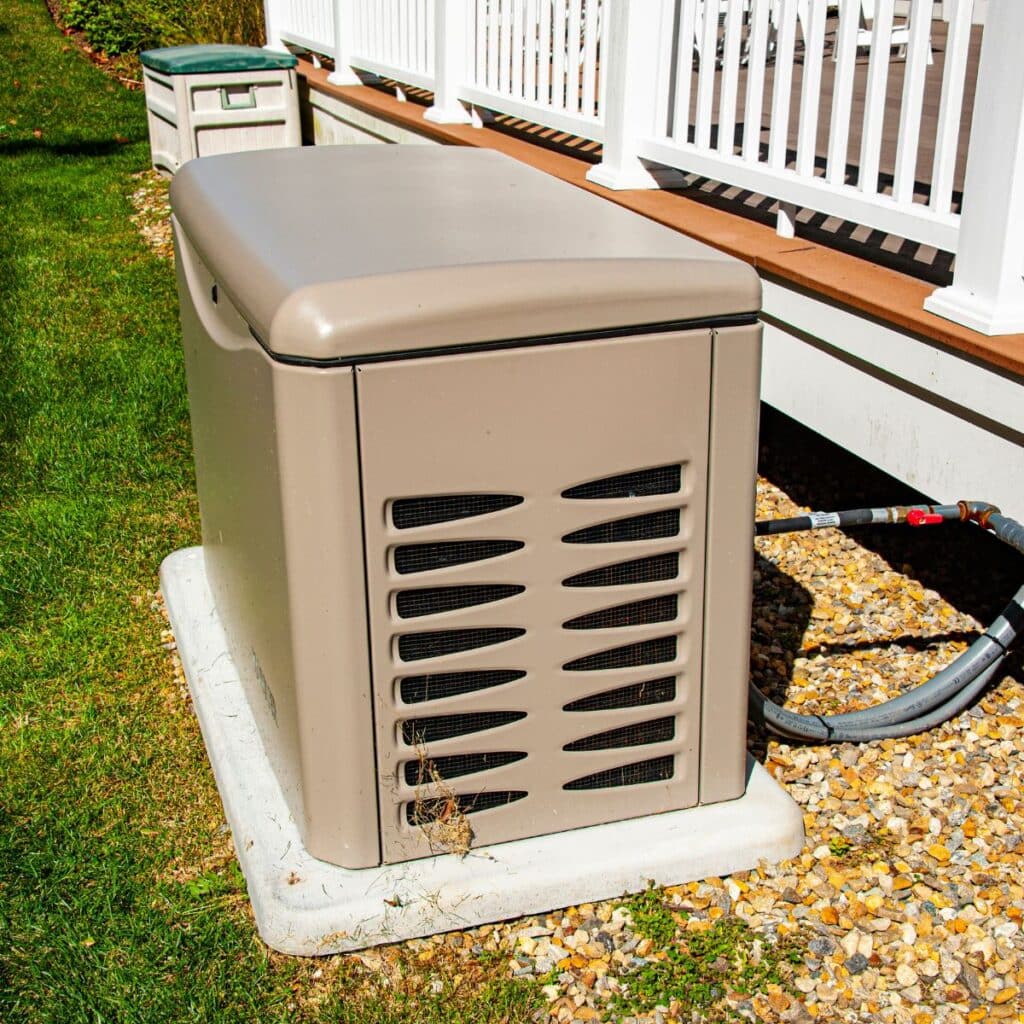 A standby generator unit is installed next to a residential deck