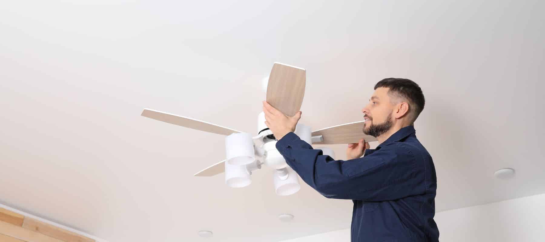Electrician installs a ceiling fan with light fixtures in a residential home