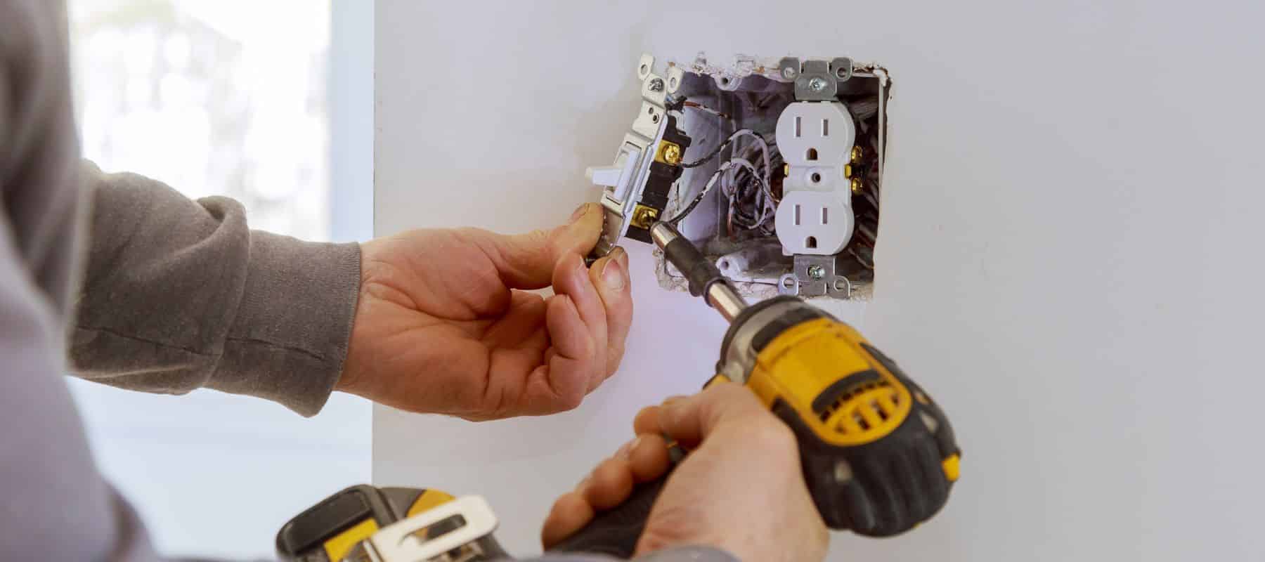 closeup of a technician performing repairs on an outlet and switch