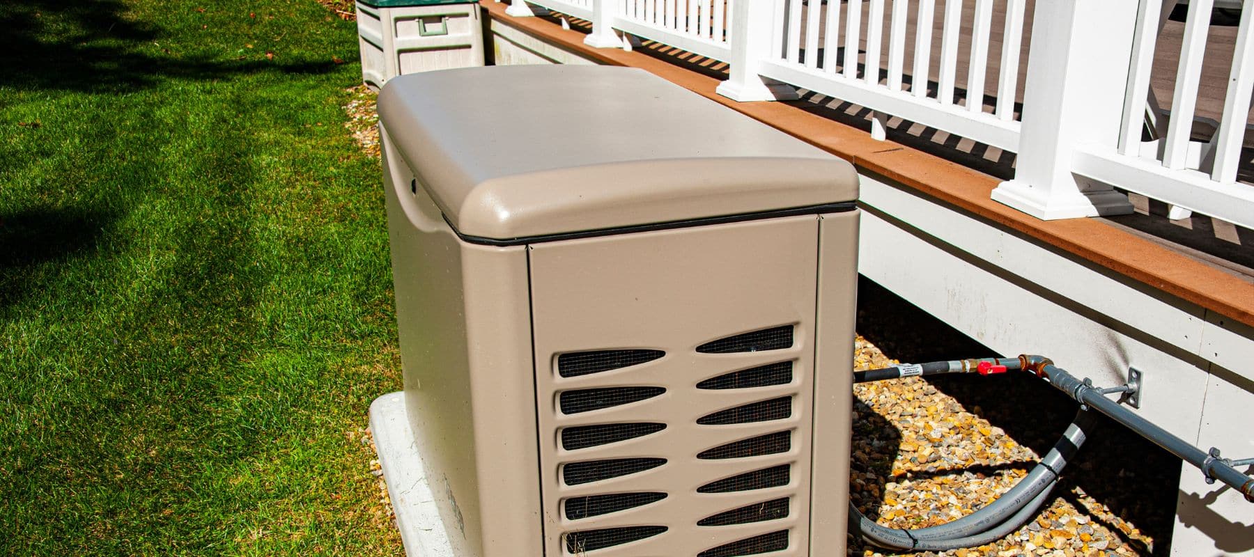 A standby generator unit is installed next to a residential deck