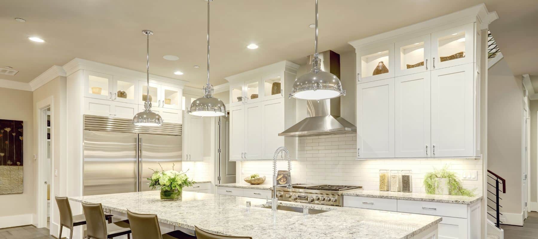 Modern kitchen with pendant lights, recessed lighting, and under-cabinet lighting illuminating white cabinetry and granite countertops