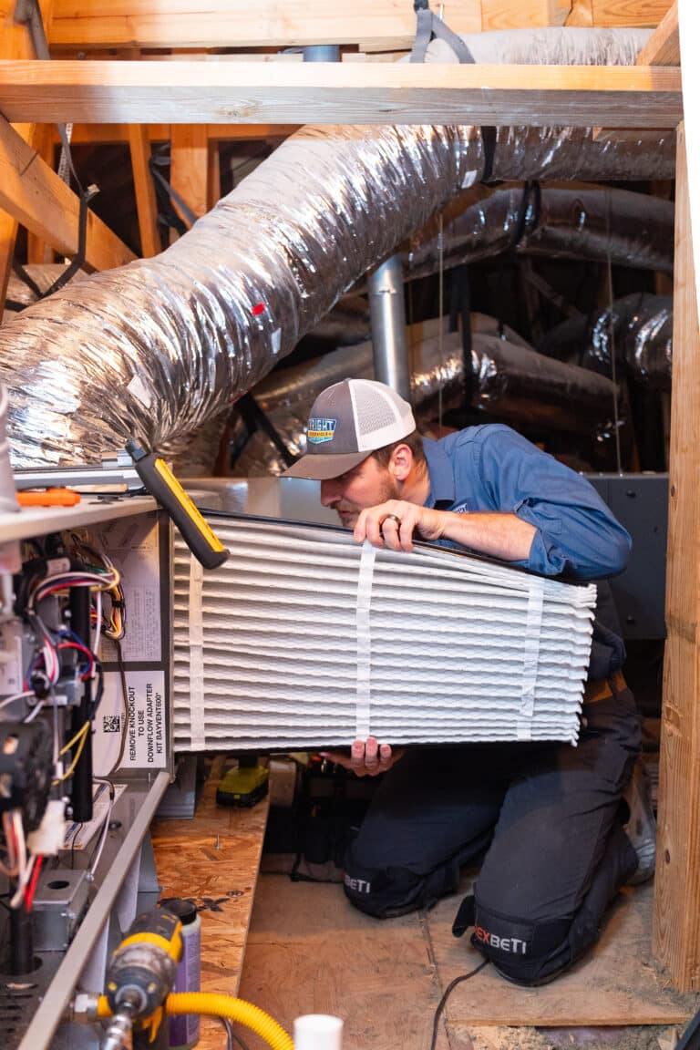 A Wright Home Services HVAC technician installing a new media filter into an HVAC horizontal system