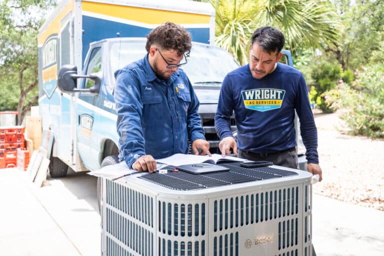 Two Wright Services installers checking a new AC unit before installing.