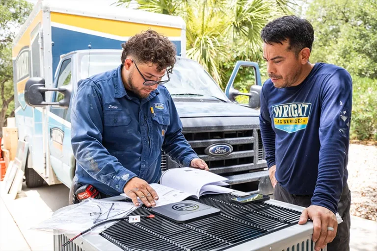 Two technicians discussing air conditioning unit.