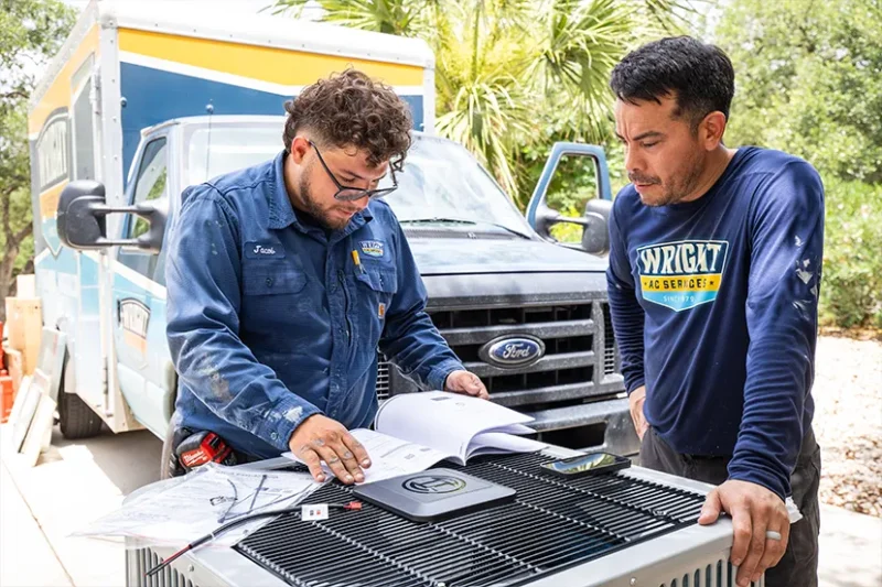 Two technicians discussing air conditioning unit.