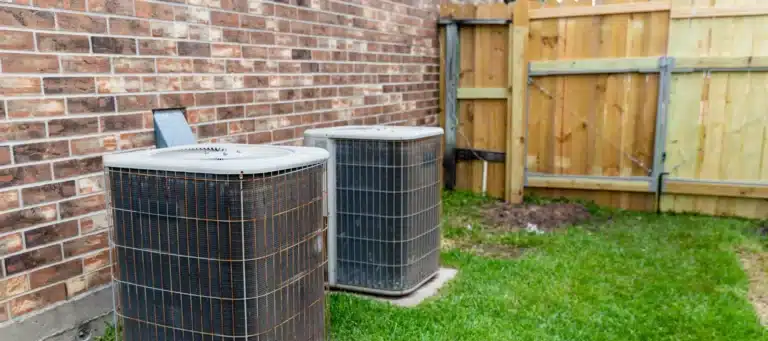 old hvac units placed outside of a brick house