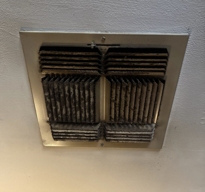 An air vent with black and gray spots indicating microbial growth.