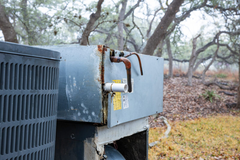 A close up image of an old, worn HVAC system sitting outside.