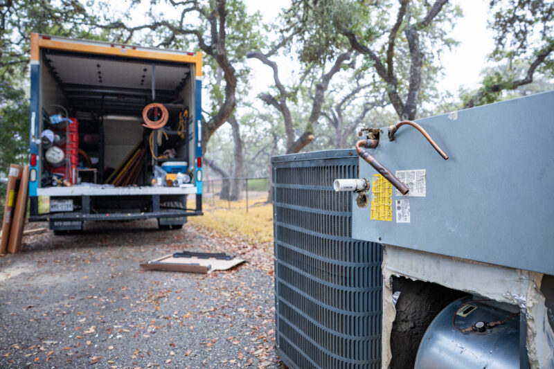 An old HVAC system sitting outside of an open box truck.