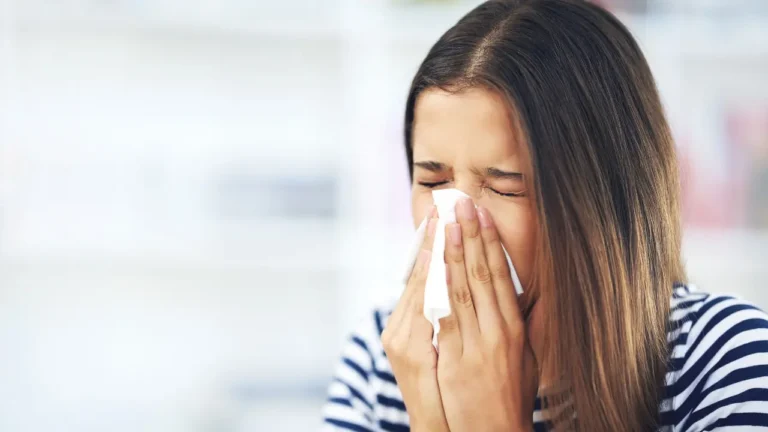 A woman sneezing into a tissue.