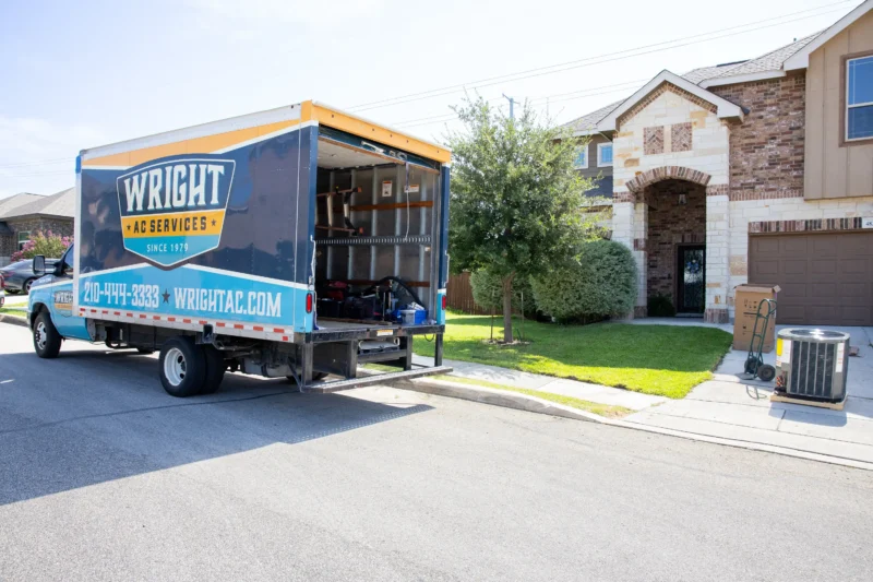 A Wright Home Services truck sitting in front of a home with old AC equipment in the driveway.
